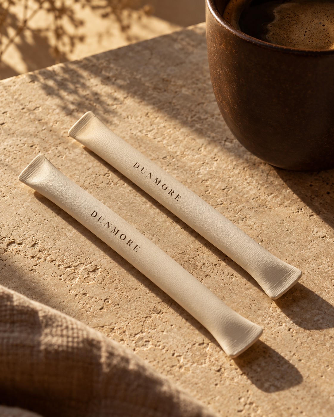 An early DUNMORE tube design in a warm, matte finish beside a cup of coffee.